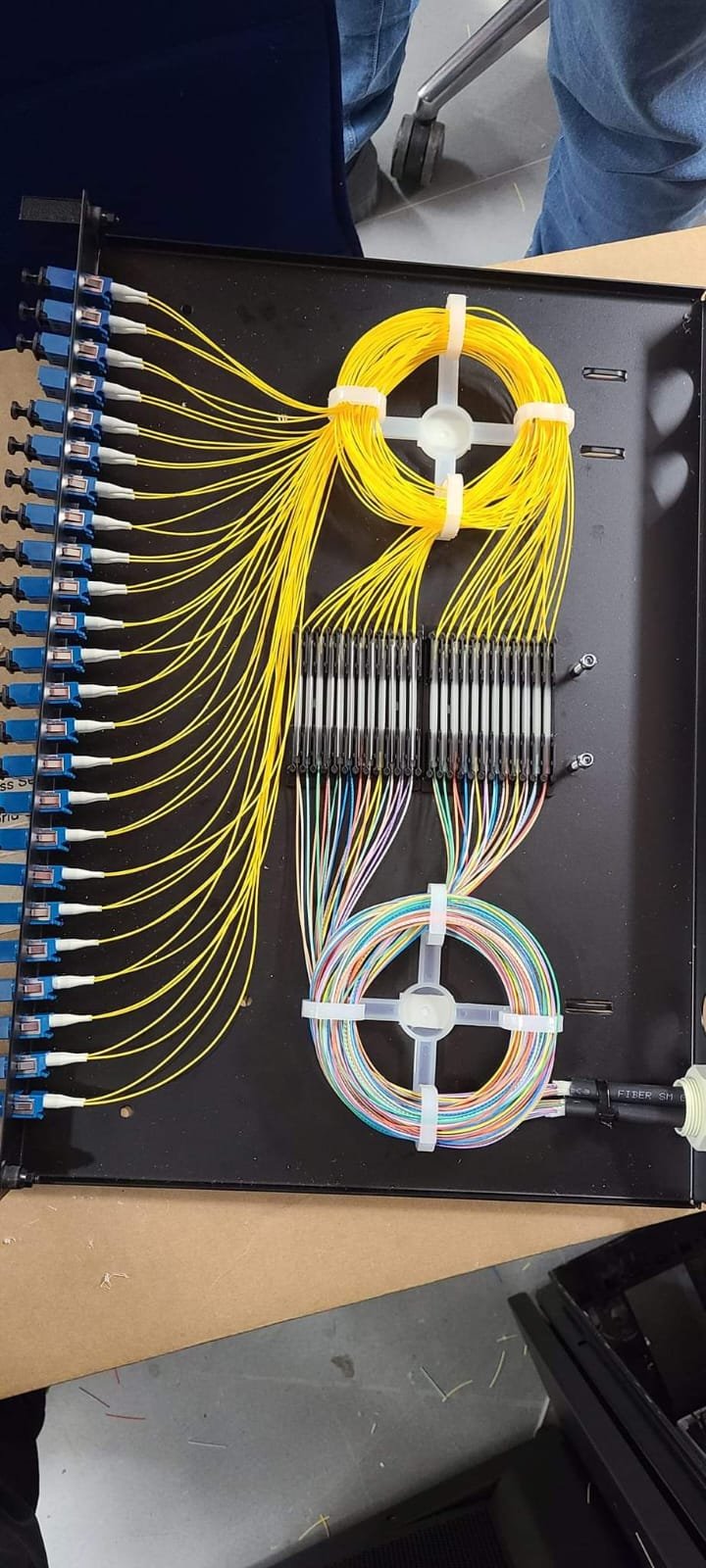 Open fibre splice tray showing organised yellow fibre leads and splice holders