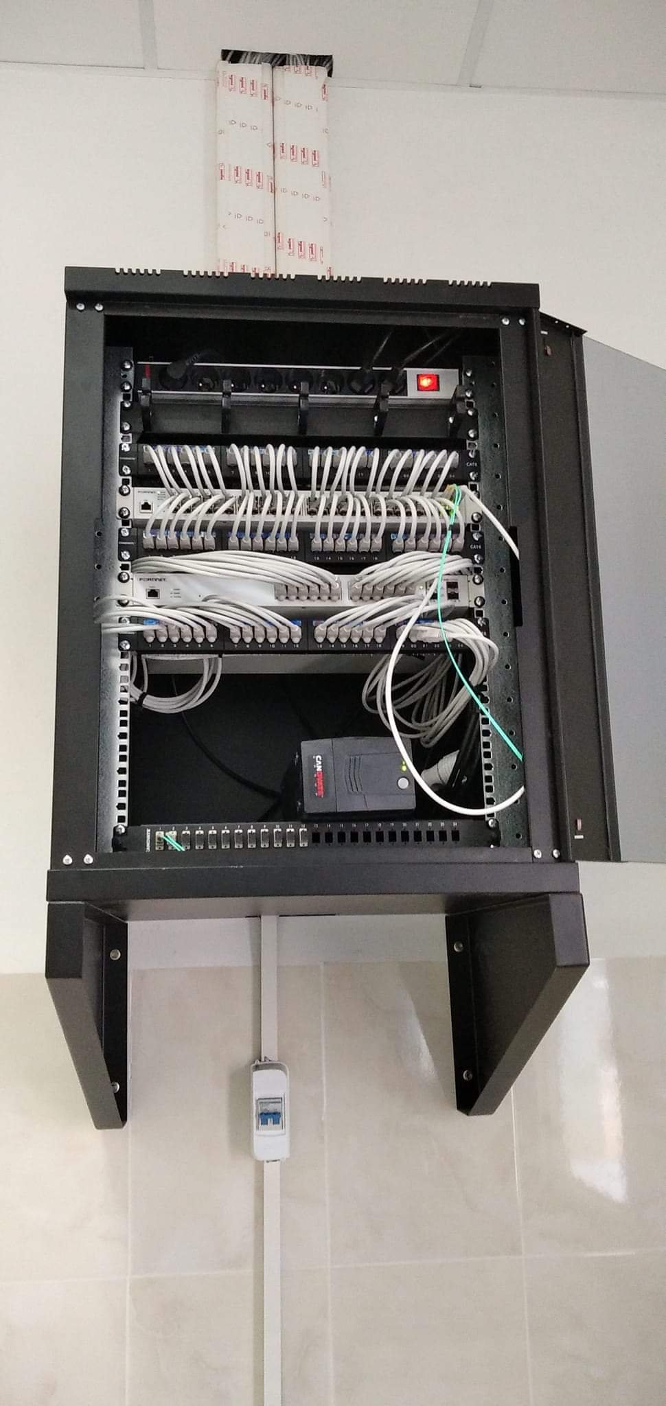 Wall-mounted black network cabinet with white patch cables